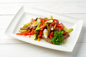 Beef salad with vegetables served on white plate