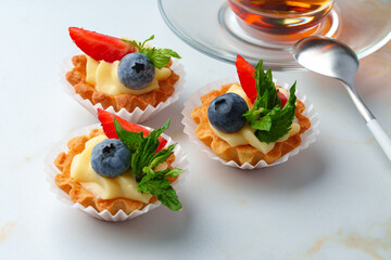Tartalette with boiled milk cream and berries on white table