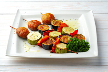 Grill vegetable kebabs on skewers in white plate
