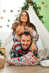 Happy parents play with their little son in a teepee during Christmas holidays © fotofabrika
