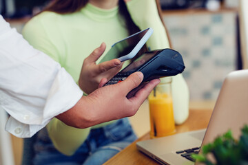 Young woman making card payment in cafeteria.