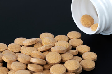 pills scattered next to a bottle of pills on a dark background