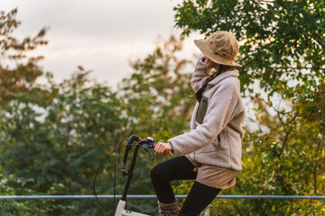 アウトドア系のファッションで夕焼けを見る自転車に乗ったアジア人女性の後ろ姿（サイクリング）
