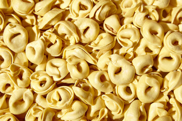 Tortellini pasta with prosciutto, food background, top view. Italian stuffed pasta