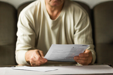 Senior man received a letter with utility bill and debts in period of energy crisis. High heating prices concept.