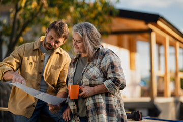 Mature couple having coffee break when working together on construction site of their new house.