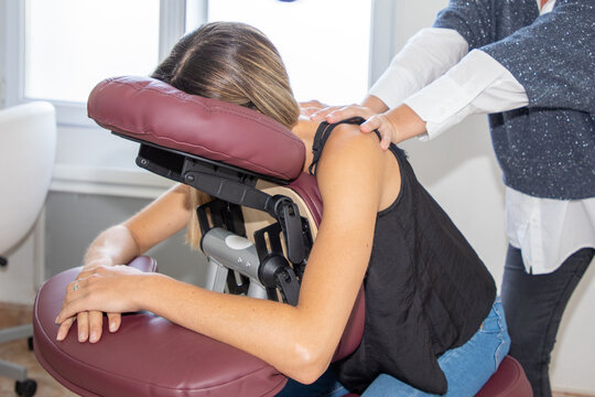 Young woman receiving back massage seated on an adapted chair