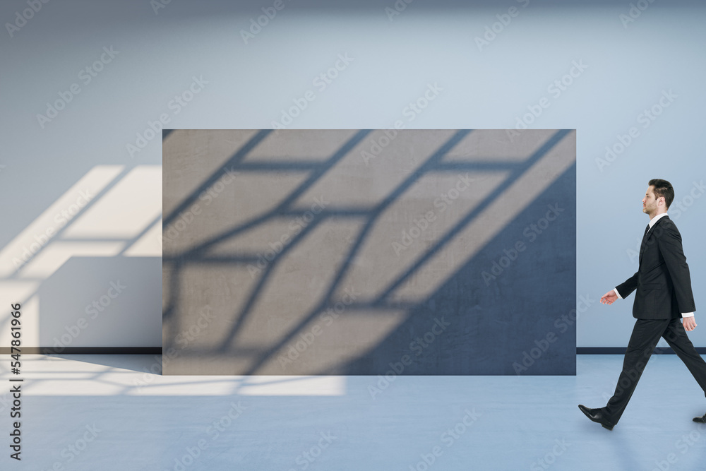 Poster side view of blurry man walking in spacious gallery interior with empty poster and sunlight shadow o