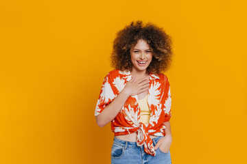 Young beautiful smiling curly woman touching her chest