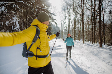 Senior couple skiing together in the middle of forest. - obrazy, fototapety, plakaty