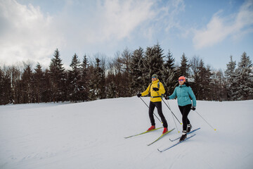 Senior couple skiing together in the middle of forest.