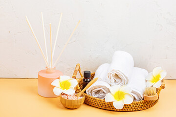 Spa massage Aromatherapy body care background. Spa herbal balls, cosmetics, towel and tropical flowers on orange table. Top view, flat lay, overhead, copy space. Beauty and health care concept