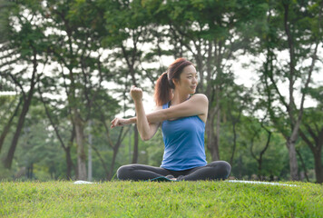 Naklejka na ściany i meble young asian woman doing yoga in the park.cold yoga is a popular yoga practice,practicing in a well ventilated area like a park or playing in a room with normal,can practice for a long time
