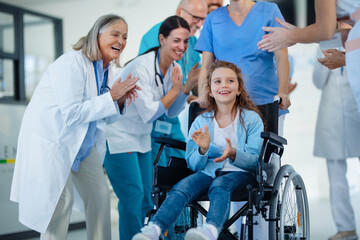 Medical staff clapping to little girl patient who recovered from serious illness.