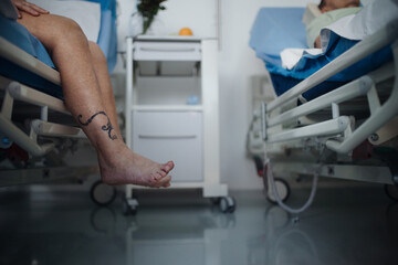 Close-up of womans leg trying to get out of hospital bed.