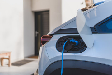 Charging an electric car in home, sustainable and economic transportation concept.