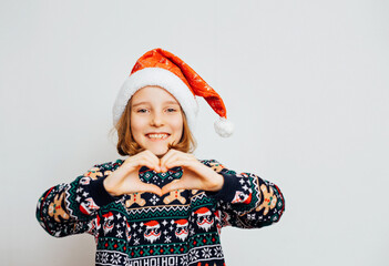 Cute girl in Santa Claus hat makes a heart symbol