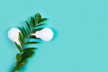 Light bulbs with fresh leaves on a green background.