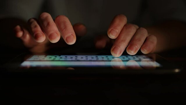 Human hands typing text on tablet touch screen keyboard 