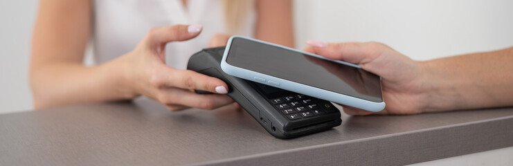 A woman pays using a non -contact payment of the NFC used by a smartphone. Widescreen. 