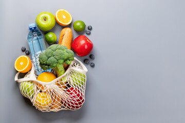 Shopping mesh bag full of healthy food on grey