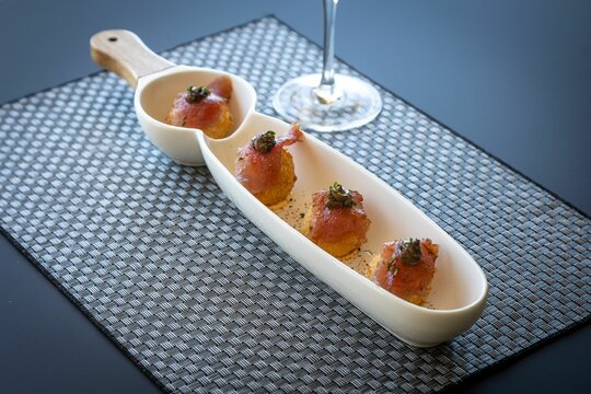 Closeup of delicious fish rolls amuse bouche served as appetizer in white plate on gray table mat