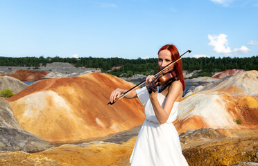 beautiful girl in white dress plays the viola (violin) against the backdrop mars landscape