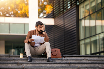 Businessman sitting on the stairs and read some documents