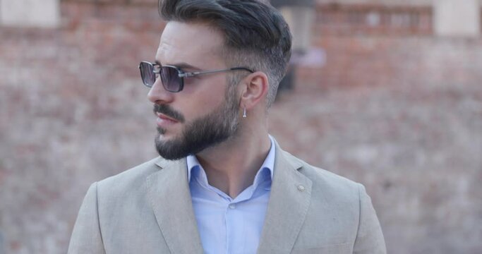 close up of sexy young man looking to side and arranging sunglasses outside in a medieval city from Transylvania