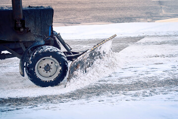 Tractor with plow remove snow from sidewalk during blizzard. Tractor clear snow from pedestrian...