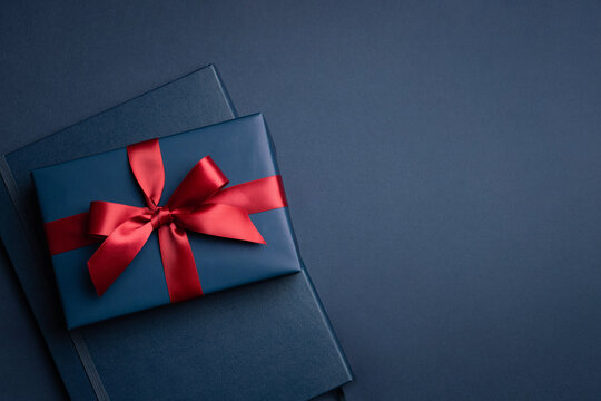 Blue gift box and notebook on dark blue background. Greeting card for businessmen.