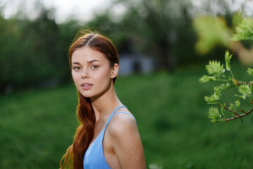 Naklejka premium Portrait of a young woman with a beautiful smile with teeth in nature on the background of trees in the spring on a sunny day, the beauty of health and youth, happiness, freedom