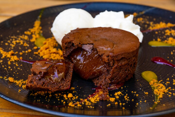 Plate of delicious warm dessert chocolate cake Fondant served with ice-cream balls. Lava cake on a decorated plate.