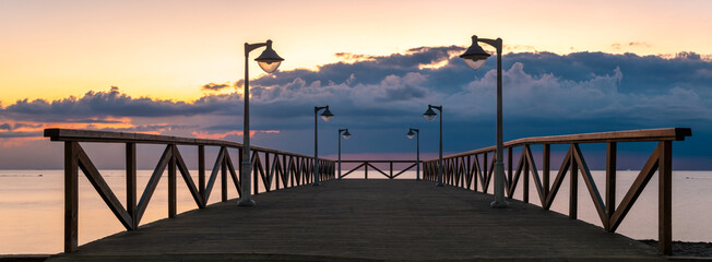 Houten pier met stijlvolle lampen tijdens stormachtige zonsopgang