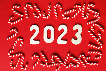 Christmas composition with candy canes and number 2023 on a red background. Copy space for text