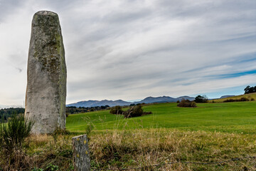 menhir de pierre imposant avec au loin les montagnes du Sancy par une belle journ&eacute;e d'automne au bord du chemin de randonn&eacute;e du lac d'Aydat dans le puy de d&ocirc;me
