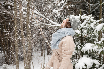 A cute girl is standing under the snow with her eyes closed