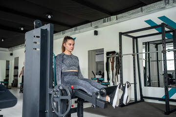 young beautiful girl in a sports gray suit works out in the gym.