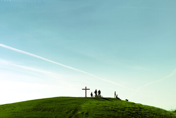 Naklejka na ściany i meble People around big cross on a green hill