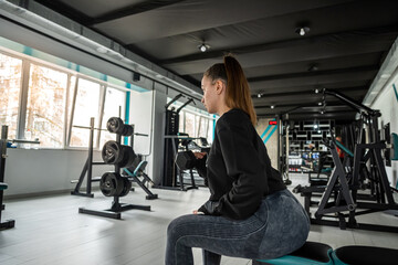 attractive young woman works on her own body and does fitness in a sports club.