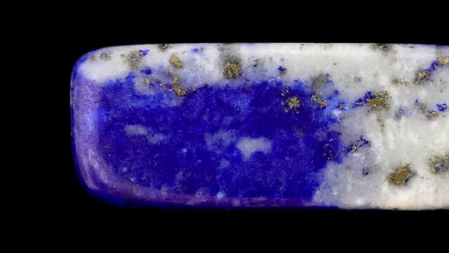 Lapis lazuli jewel stone texture on black background. Macro closeup. Moving right seamless loop backdrop.