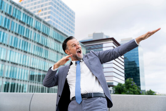 Happy mature businessman dancing in front of building