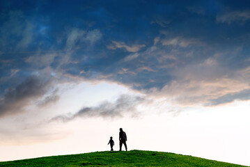 Silhouette of a person following child against minimalist landscape