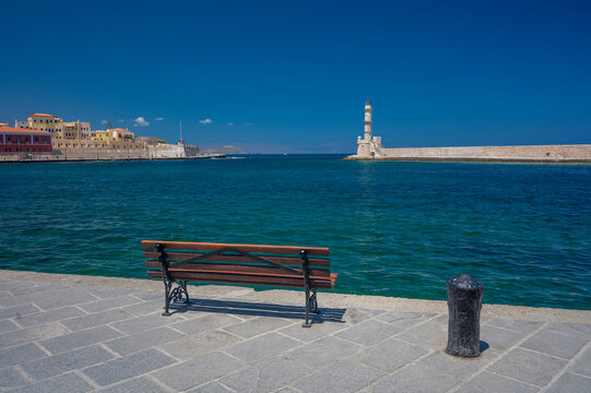 Greece, Crete,&nbsp;Chania,&nbsp;Empty harbor bench with lighthouse in background