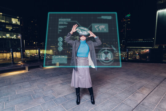 Woman using virtual reality glasses on footpath at night