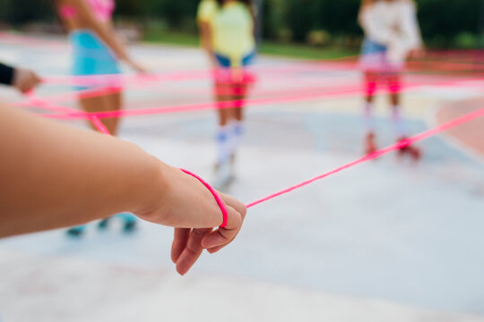 Hands of woman with friends holding pink string at sports court