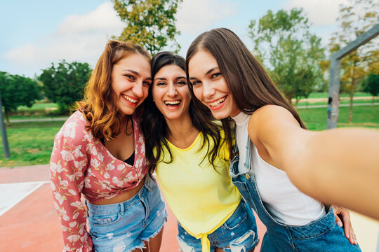 Happy woman with friends taking selfie at sports court