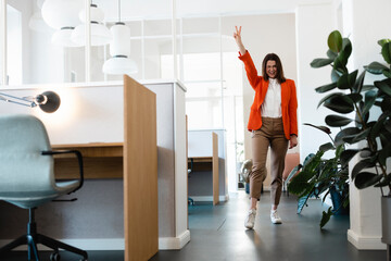 Happy businesswoman gesturing peace in office