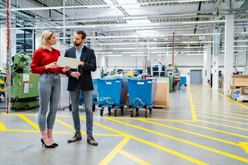 Business colleagues discussing with each other standing by markings in production hall