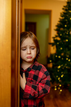 Sad boy standing near doorway at home